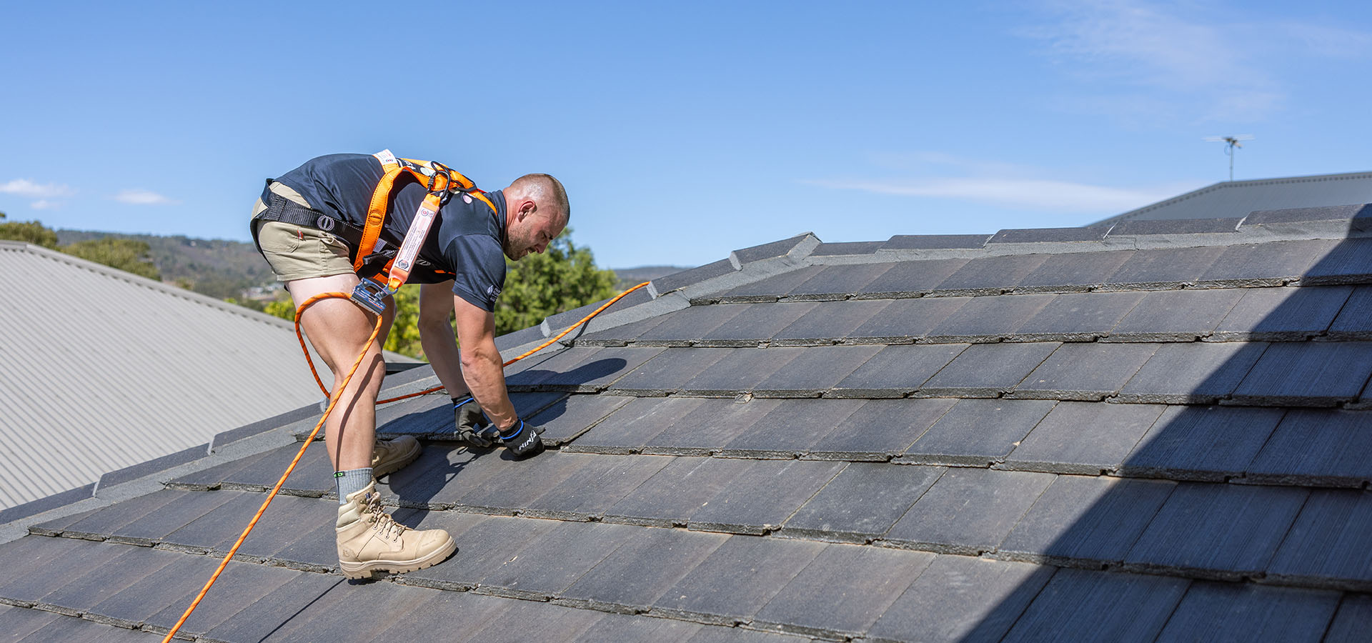 QACO roofer in a safety harness carrying out a roof replacement